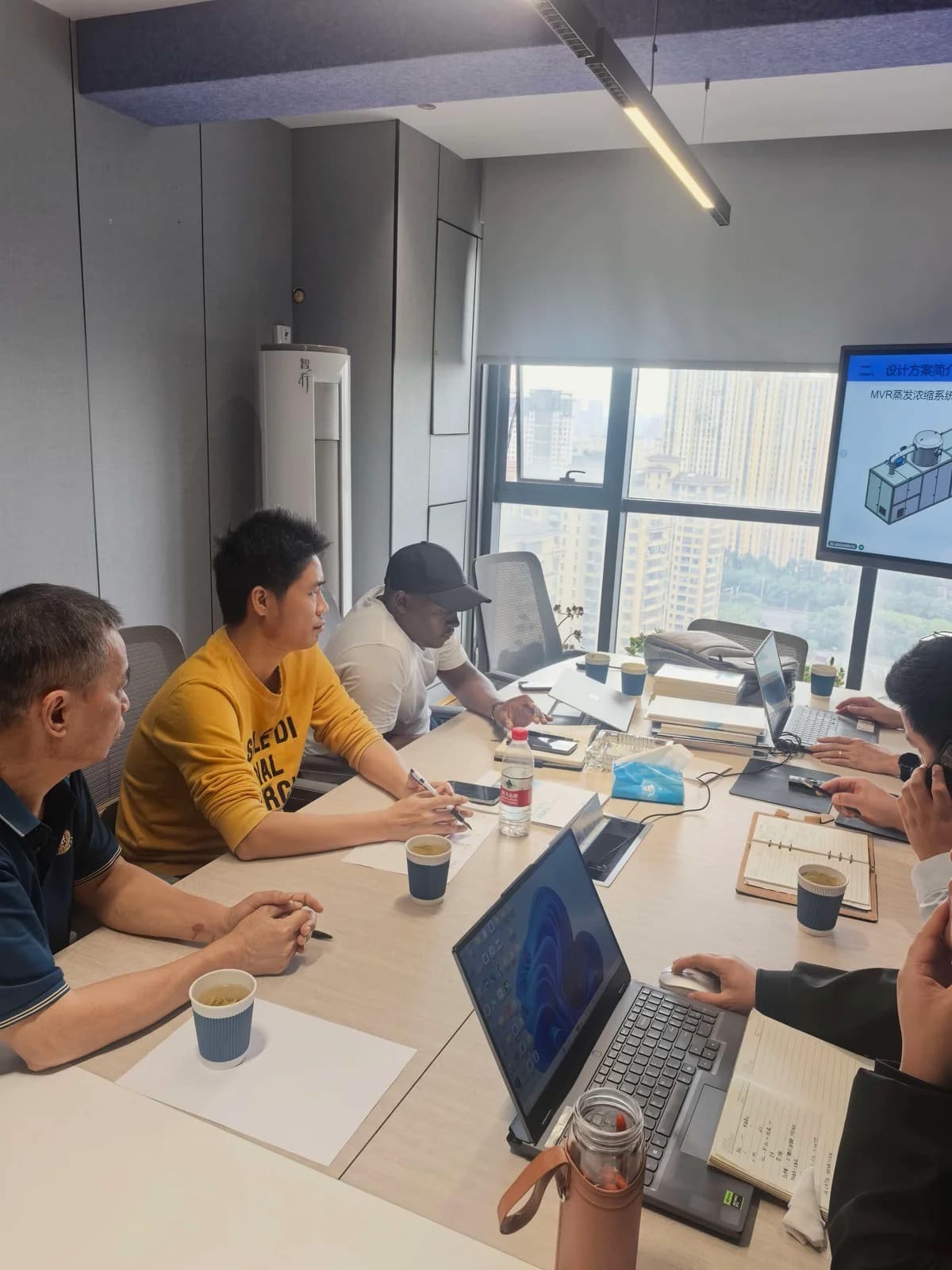 Kenyan customer and BHP engineering team in a technical session at the BHP Jiangsu branch, with an MVR evaporation and concentration system design scheme on the meeting room screen